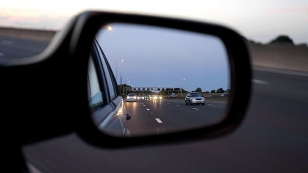 A side view mirror showing visibility of cars driving on the road.